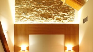 A hotel room with a large bed, wooden headboard, two bedside tables with lamps, and a bench.