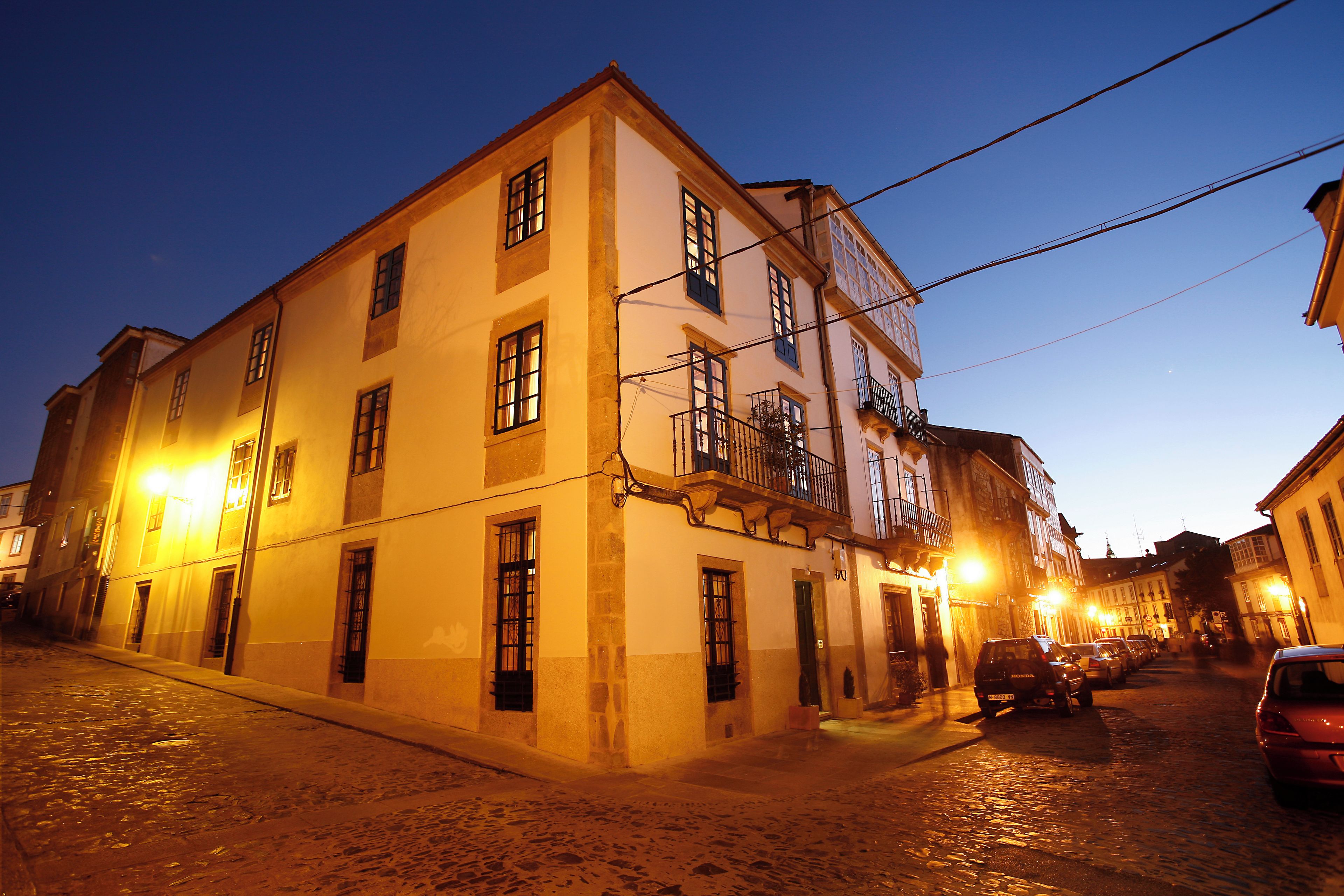 A historic building with multiple windows and a balcony, situated on a cobblestone street.