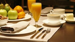 A breakfast setting with a table set for two, including fruits, juice, coffee, and butter. - Hotel Altair (Santiago de Compostela)
