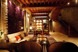 A cozy living room with a stone wall, wooden ceiling, and a staircase. - Hotel Altair (Santiago de Compostela)