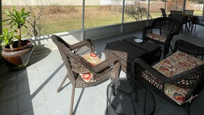 A covered patio area with wicker furniture and a potted plant.