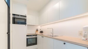 A modern kitchen with white cabinets, a built-in oven, a sink, and a coffee maker. - Seaview 4 with parking by Interhome (Bredene)
