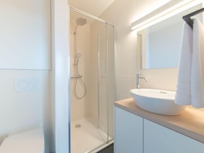 A modern bathroom with a glass shower enclosure, a white sink, and a mirror above it. - Seaview 4 with parking by Interhome (Bredene)