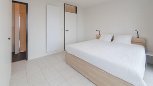 A modern bedroom with a single bed, a wooden headboard, and a white door. - Seaview 4 with parking by Interhome (Bredene)