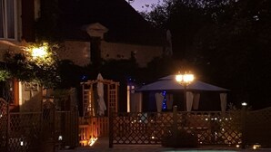 Una piscina con plataforma de madera y zona de estar cubierta.