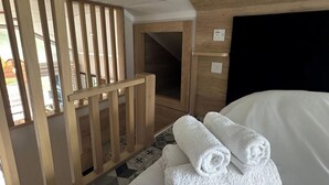 A hotel room with a bed, a wooden crib, and a pair of rolled towels. - 2 Bed Inverness - Sleeps 4 - Parking - Wifi (Inverness)