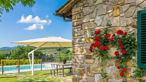 Ein Steinhaus mit Pool, Sitzgelegenheiten im Freien und einer Pergola.