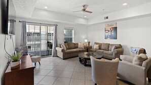 A spacious living room with a large sectional sofa, a coffee table, and a TV mounted on the wall. - Full house (Myrtle Beach)