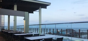 A restaurant with outdoor seating overlooking the ocean, featuring a high ceiling and large windows. - chill pill (Myrtle Beach)