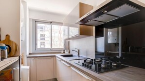 Eine moderne Küche mit großem Fenster, Edelstahlgeräten und hellen Küchenschränken.