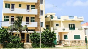 A multi-story residential building with balconies, a palm tree, and a clear sky. - Beautiful Deluxe Double Room in the City Center - Wifi and Ac (Vila do Maio)