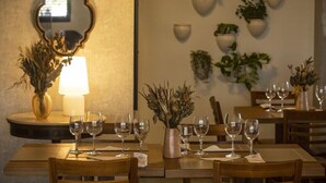 Un espace repas avec des tables et des chaises en bois, un miroir et des jardinières murales ornées de plantes vertes.