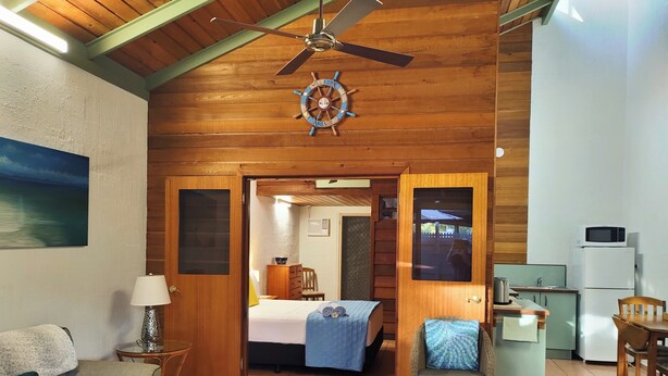 A cozy room with a bed, a sofa, a dining table, and a kitchenette. - Beachside Cottage - A Private Peaceful Hidden Gem (Nelly Bay)
