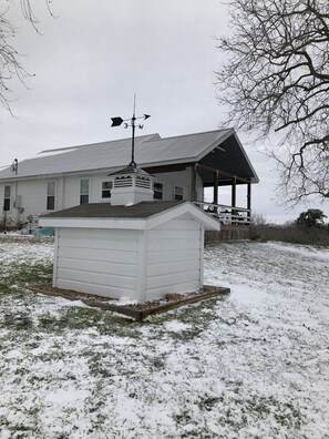 A white building with a covered porch and a small shed in front. - Guest House at the Brown Ranch (La Grange)
