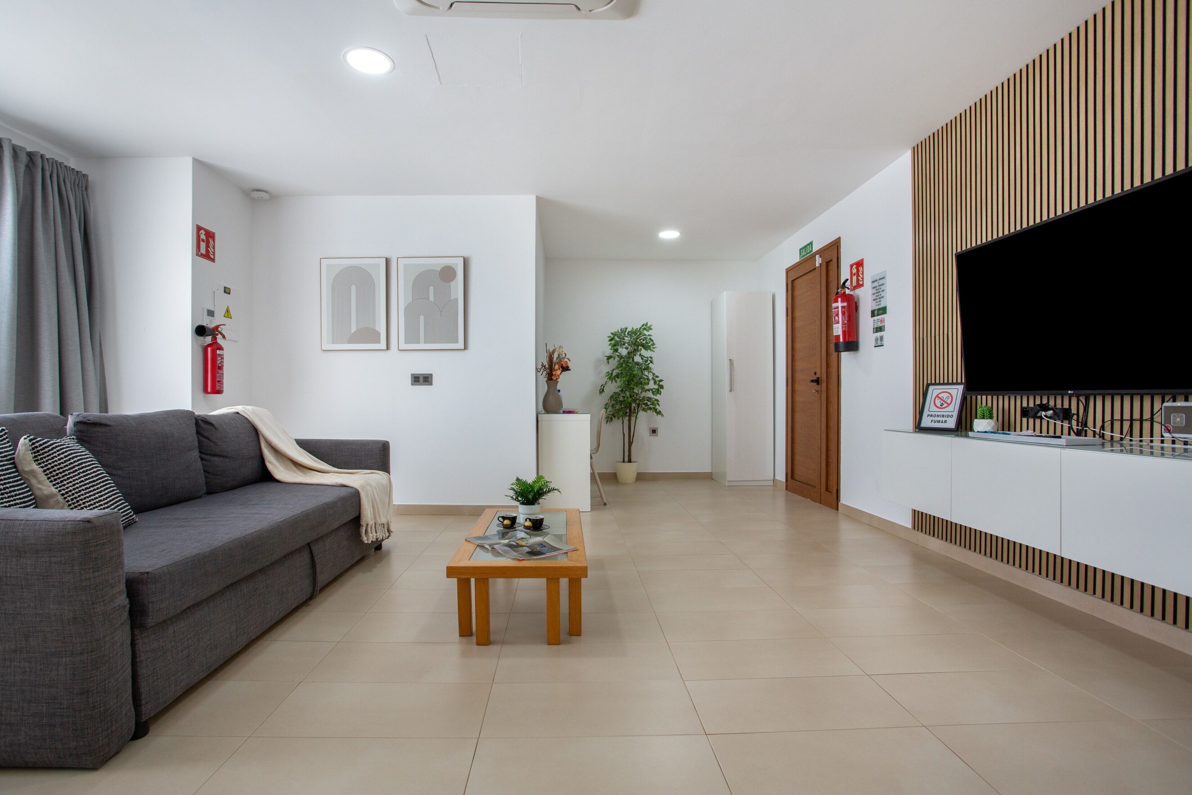 A modern living room with a sofa, a coffee table, and a flat-screen TV mounted on the wall.