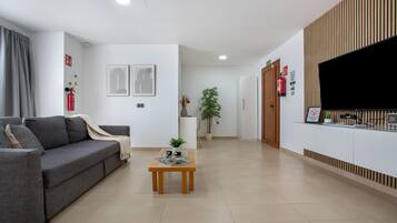 A modern living room with a sofa, a coffee table, and a flat-screen TV mounted on the wall.