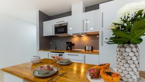 A modern kitchen with white cabinets, a wooden countertop, and a decorative vase with flowers.