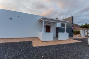 Un edificio moderno con fachada blanca, un vestíbulo cubierto y un camino de entrada de grava.