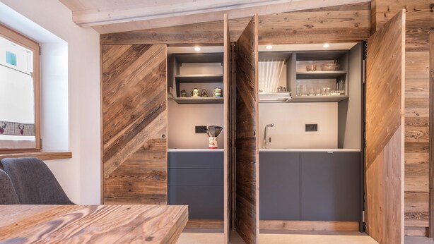Une cuisine moderne avec des éléments en bois, des étagères intégrées et un coin repas doté d’une table en bois.