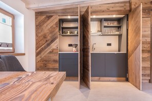 A modern kitchen with wooden accents, built-in shelves, and a dining area with a wooden table.