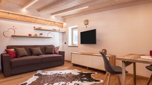 Un salon confortable avec un canapé, une table à manger, un téléviseur et un tapis en peau de vache.