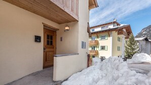 Un bâtiment avec une porte en bois, un petit balcon et un sol recouvert de neige.