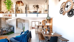 Un grand espace de vie comprenant un canapé, une table à manger et un escalier menant à l’étage supérieur.