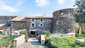 Un bâtiment en pierre doté d’une cour, d’un espace extérieur aménagé pour s’asseoir et d’un grand mur en pierre.