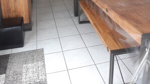 Eine moderne Küche mit dunklen Schränken, einer zentralen Kochinsel und einem Essbereich mit Holztisch und -stühlen.