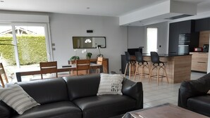 Ein modernes Wohnzimmer mit einer schwarzen Ledersofa, einem Holztisch und einem Essbereich mit Holztisch und Stühlen.