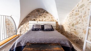 Un dormitorio con pared de piedra, un banco de madera y una barandilla de metal.