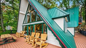 A wooden deck with Adirondack chairs and a picnic table.