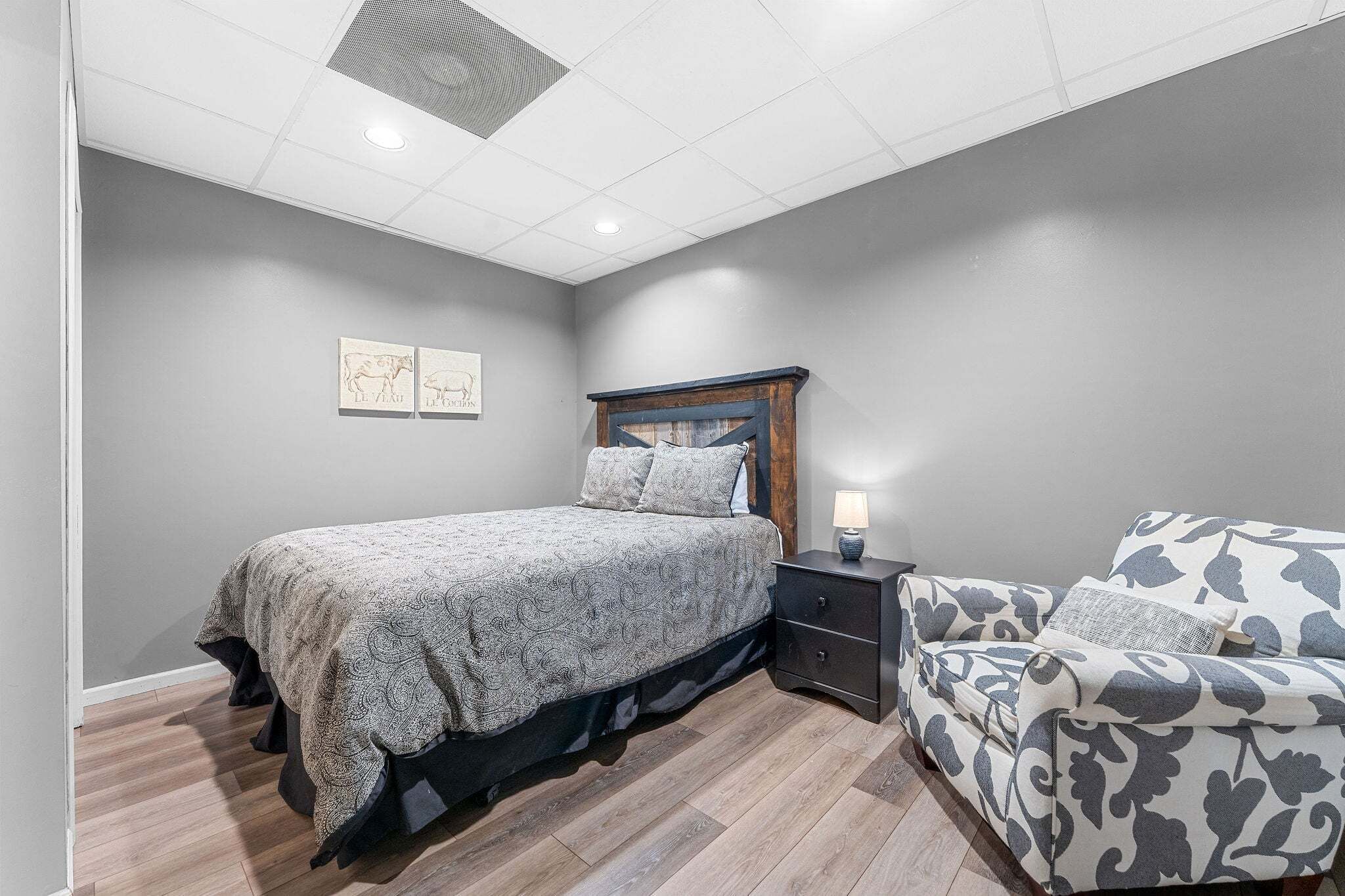 Une chambre à coucher avec un lit, une table de chevet, une lampe et un fauteuil à motifs.