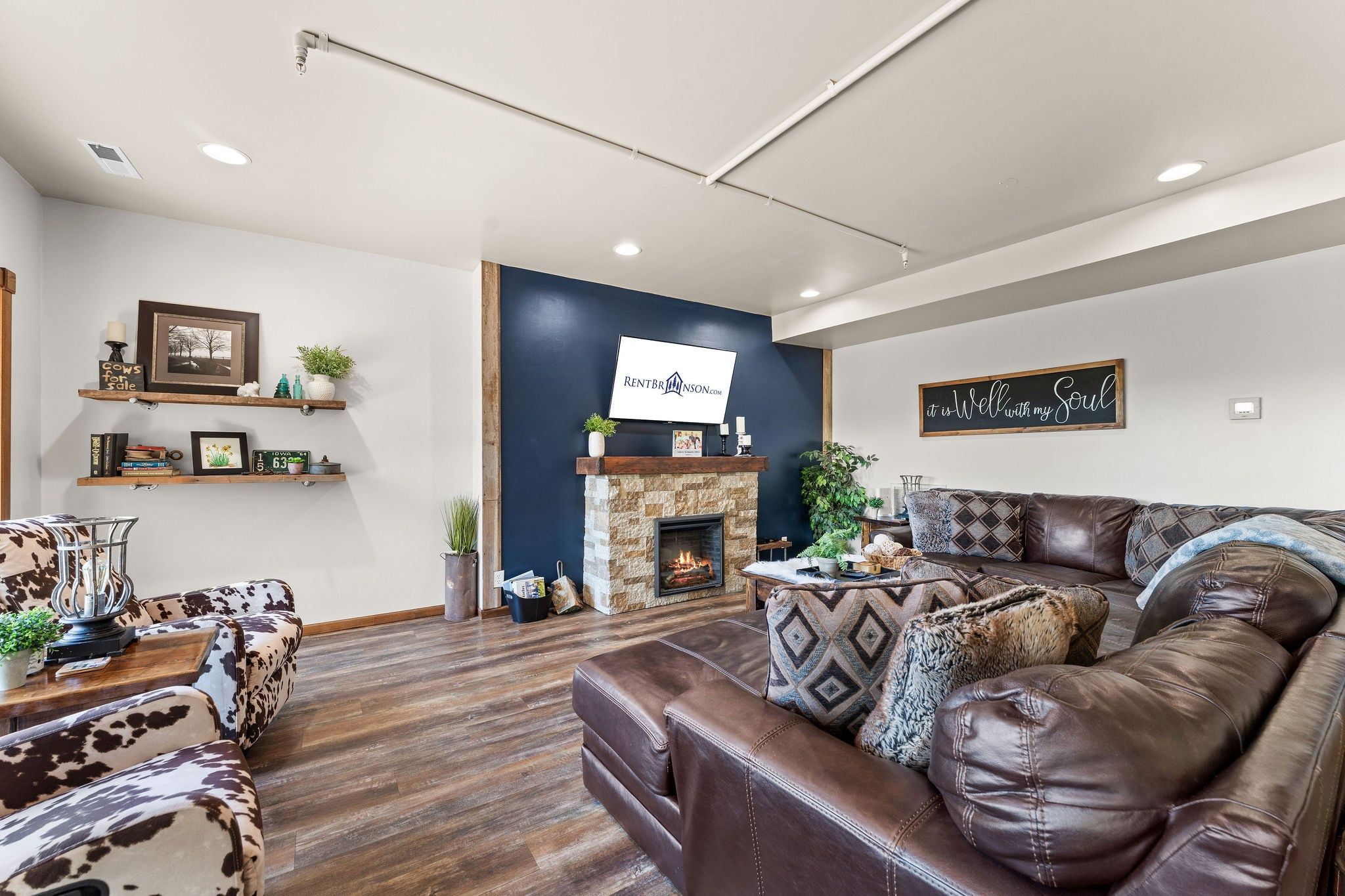 Ein Wohnzimmer mit Kamin, Ledersofa und einem an der Wand befestigten Fernseher.