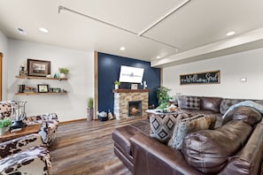 A living room with a fireplace, leather sofa, and a mounted television.