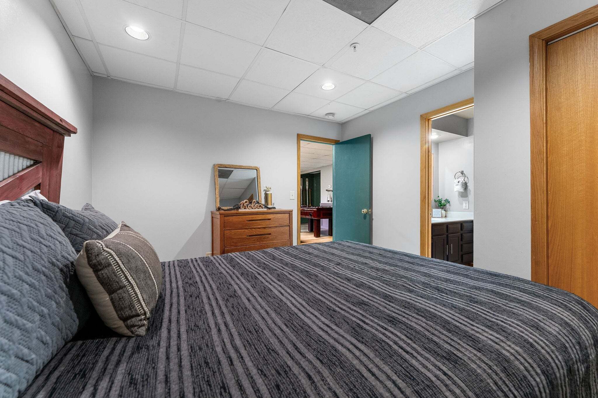 A bedroom with a bed, dresser, and a mirror.