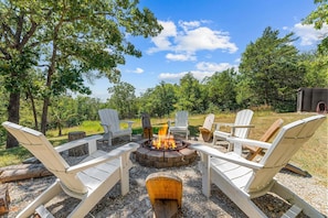 An outdoor seating area with Adirondack chairs around a central fire pit.