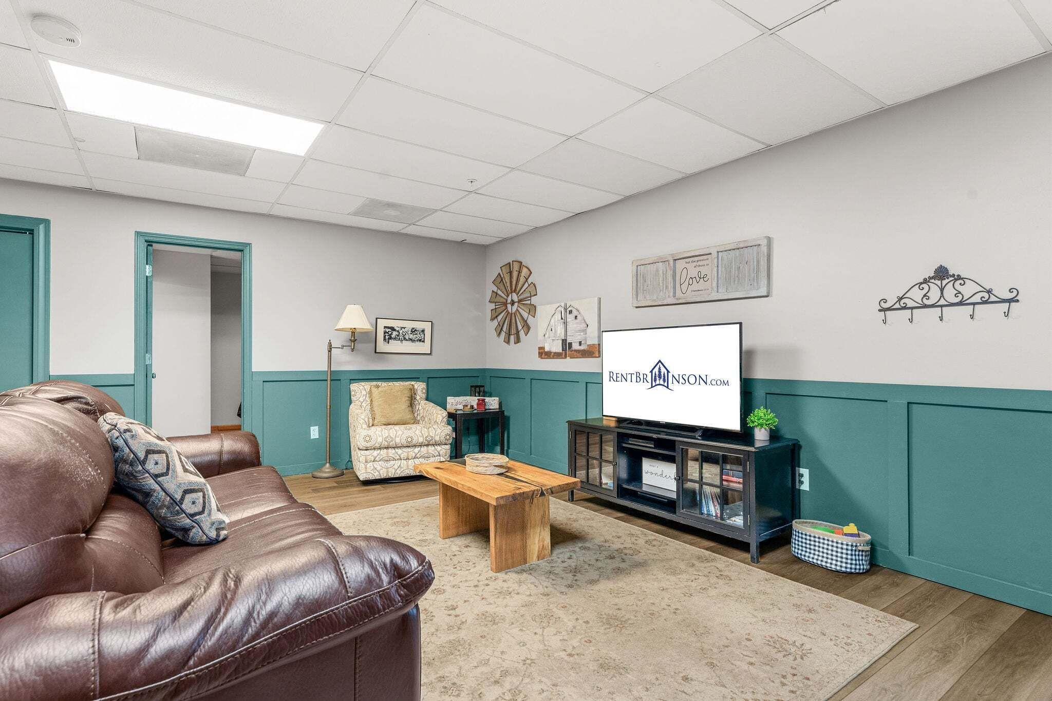 A furnished living room with a leather couch, a wooden coffee table, a television, and a cabinet with books.
