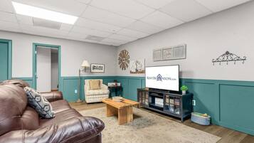 A furnished living room with a leather couch, a wooden coffee table, a television, and a cabinet with books.