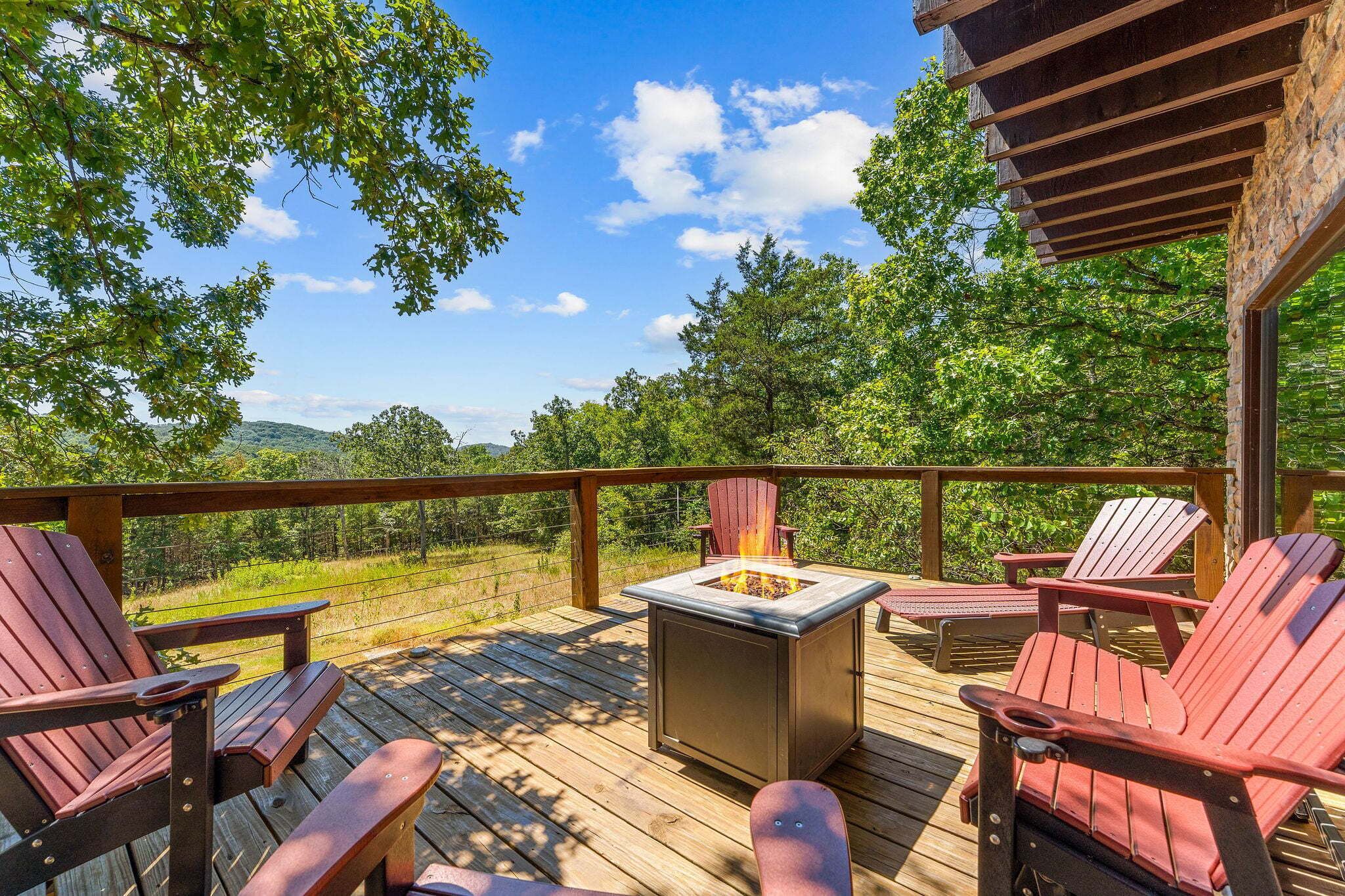 A deck with wooden chairs and a fire pit.