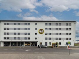 Un moderno hotel tipo bed and breakfast con fachada plana, varias ventanas y un coche estacionado adelante.