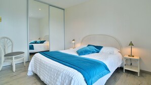 Une chambre à coucher avec un lit, des tables de chevet, une chaise et un grand miroir.