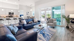 Ein modernes Wohnzimmer mit einem blauen Sofa, einem Glastisch und Blick auf die Terrasse.
