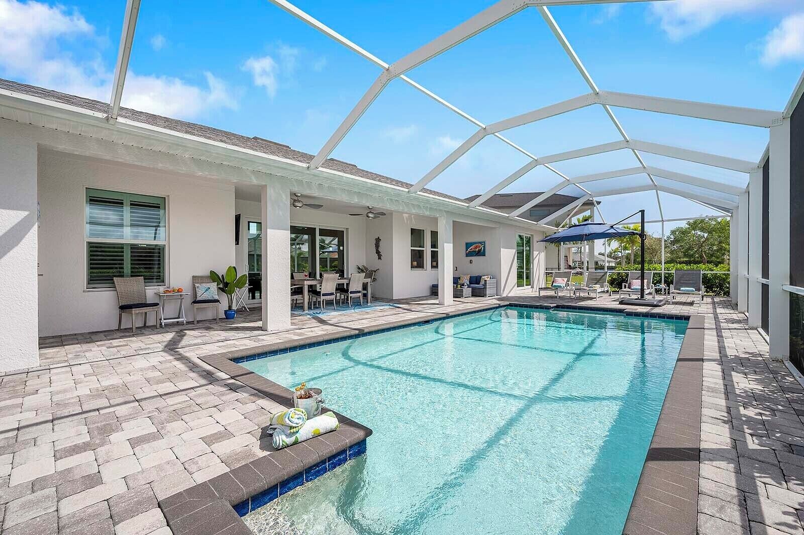 A covered swimming pool with a patio area, outdoor seating, and a view of the surrounding landscape.
