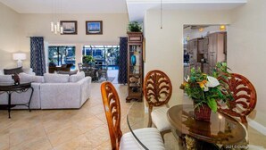 A spacious living room with a sofa, chairs, a dining table, and a view of the outside. - Summer Breeze - Gulf Access Location - Pool & Hot (Cape Coral)