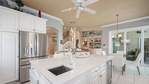 Una cocina moderna con armarios blancos, electrodomésticos de acero inoxidable y una isla grande con fregadero.