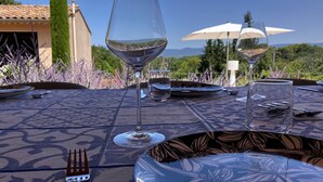 Mesa para comer al aire libre con vistas despejadas del paisaje circundante, incluyendo árboles y un edificio con tejado de tejas.