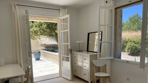 Un dormitorio con cama, escritorio, silla, cómoda y ventana con vistas a zonas verdes.