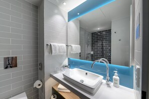 A modern bathroom with a white sink, a mirror with a blue accent, and a shower area.