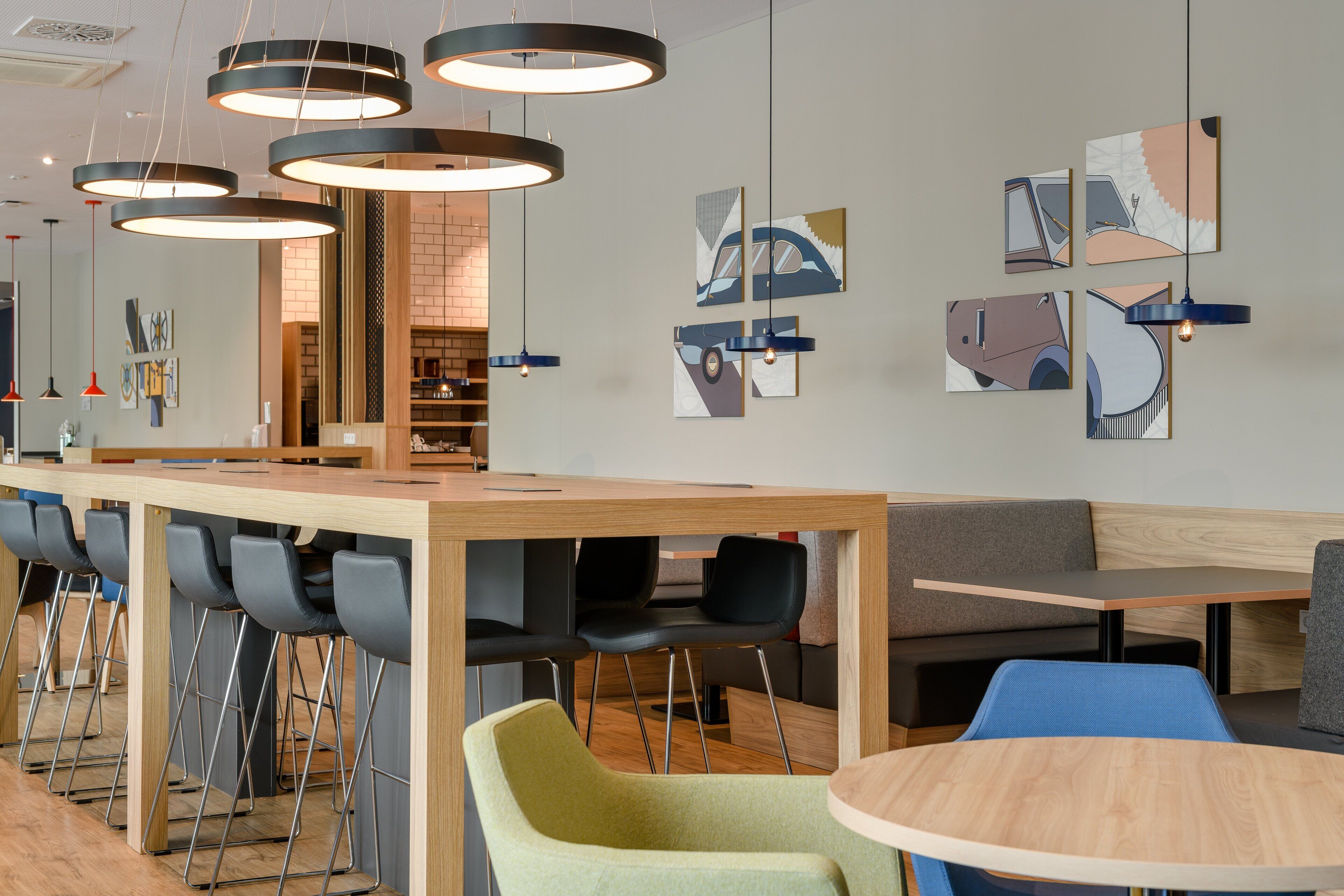 A modern bar area with multiple seating options, including bar stools and tables, and artwork on the walls.